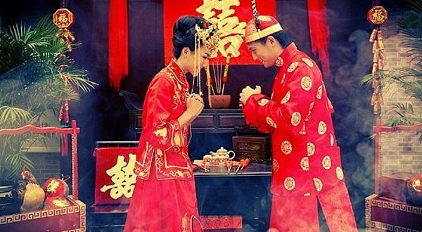Chinesisches Brautpaar in roter Hochzeitskleidung bei der traditionellen Verlobungszeremonie