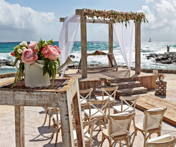 Romantische Strandhochzeit mit Blumenbogen, weißem Tüll und Meerblick
