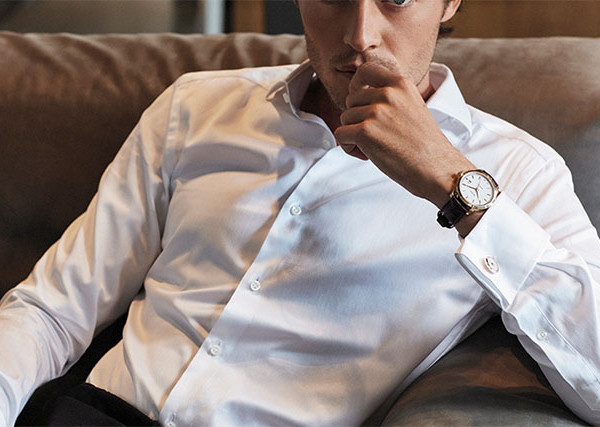 Mann in weißem Hemd mit elegantem Edelstahl-Armbanduhr mit braunem Lederarmband