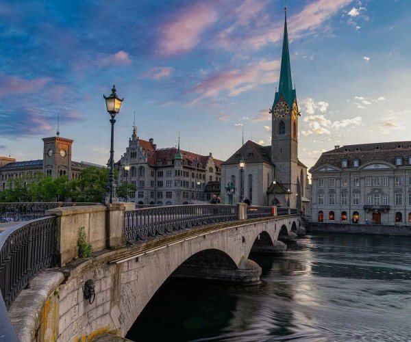 Panoramablick auf die Zürcher Altstadt mit Limmatbrücke und Kirchturm bei Sonnenuntergang