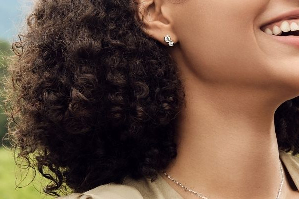 Frau mit zartem Diamant-Ohrstecker und Ring aus Weißgold mit Brillant im Freien