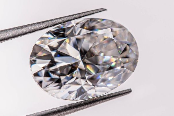Oval geschliffener Diamant in einer Pinzette, brillant facettiert mit klarem Funkeln
