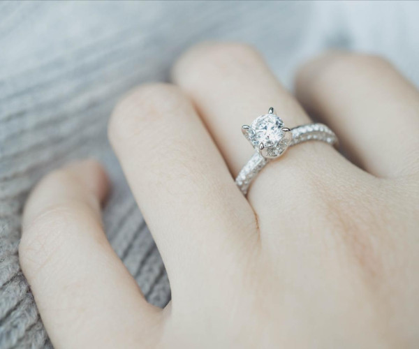 Verlobungsring aus Weißgold mit rundem Solitärdiamanten und pavébesetzter Ringschiene