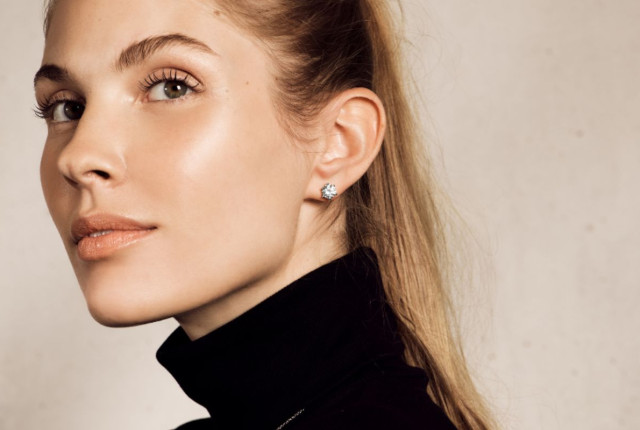 Frau mit kleinem Brillanten-Ohrstecker aus Weißgold im schlichten, funkelnden Krappen-Design