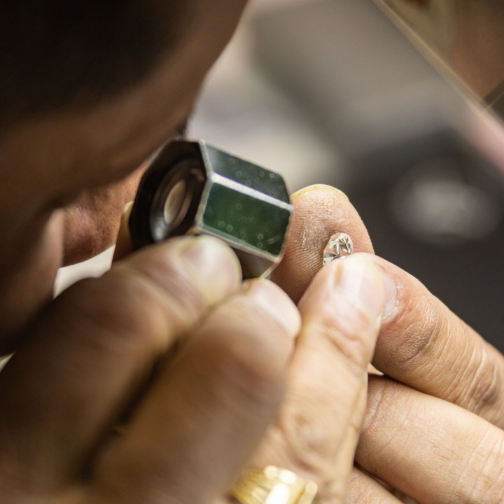 Juwelier prüft einen geschliffenen Diamanten mit Lupe beim Polieren