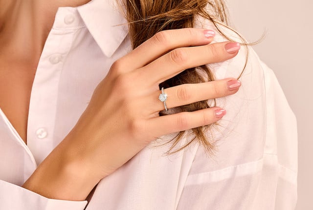 Hand mit Solitär-Diamantring in Weißgold, filigrane Krappenfassung am Ringfinger