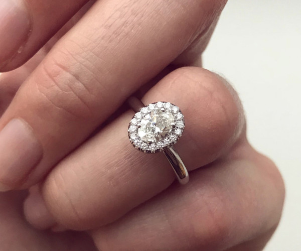 Weißgoldener Verlobungsring mit ovalem Diamanten, umgeben von funkelndem Brillantenkranz