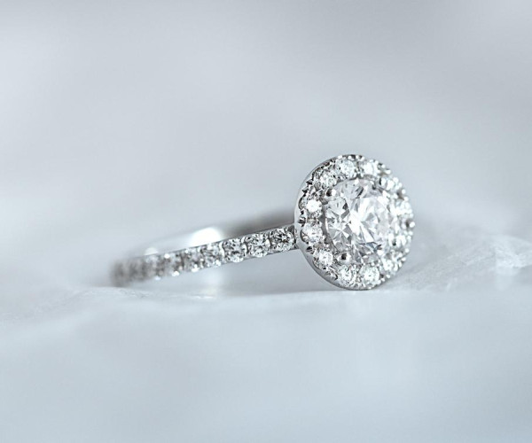 Weißgoldener Diamantring mit runder Mittelsteinfassung und pavébesetztem Ring.