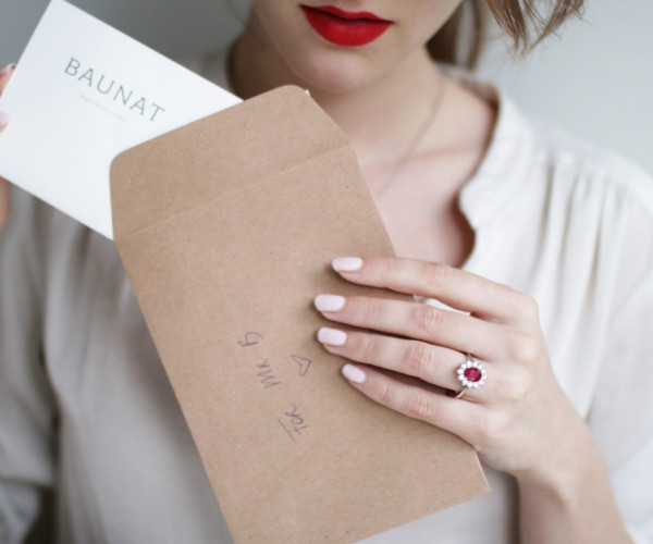 Frau mit Weißgoldring mit rotem Edelstein und kleinen Diamanten im Halo-Design