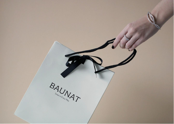 Eine Person mit einer weißen Einkaufstasche von BAUNAT nach dem Kauf von Schmuck