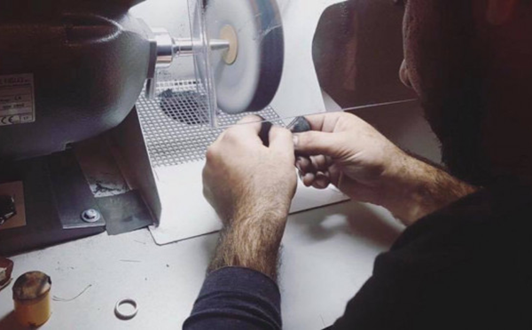 Ein Handwerker bedient in einer Werkstatt eine Maschine und konzentriert sich dabei mit Präzision und Geschick auf den Prozess des Diamantschneidens