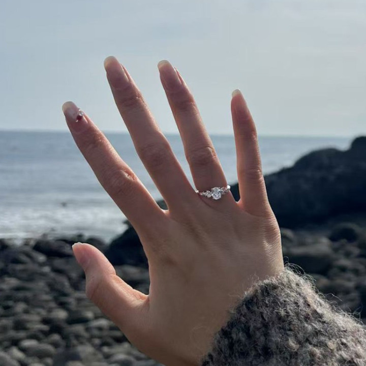 Hand mit weißgoldenem Diamantring im Vintage-Stil, zentraler Solitär mit seitlichen Akzenten