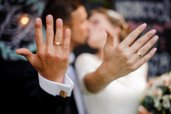 a couple kissing as they hold their hands up to the camera, celebrating their bond on their wedding day