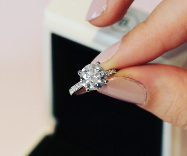 close-up of the fingers of a woman holding a brilliant cut diamond ring