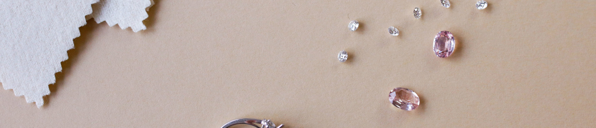White gold engagement ring with a prong-set diamond, surrounded by loose diamonds and pink gemstones Know the engagement ring price rule before you buy your diamond ring online.