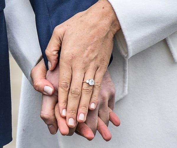 a close-up of a couple’s hands clasped tightly, featuring a diamond ring on the woman's finger