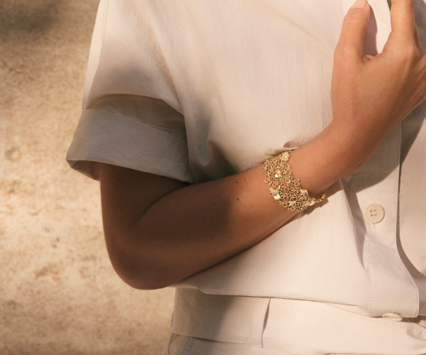 A woman in a white shirt adorned with a gold bracelet, exuding elegance and simplicity.