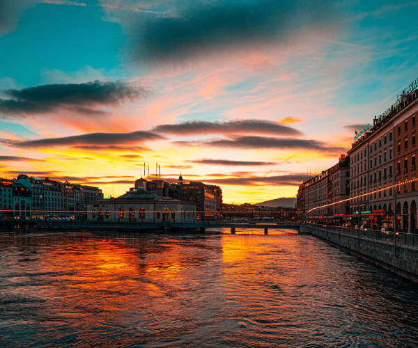 A serene river flows beneath a sturdy bridge, surrounded by lush greenery and a clear blue sky above.
