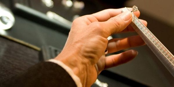 a skilled jeweller holding a ring adjustment tool, preparing to resize a ring with utmost precision and care