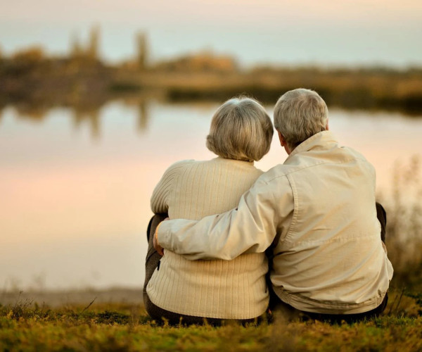 Old couple cuddling at the lakeside during sunset