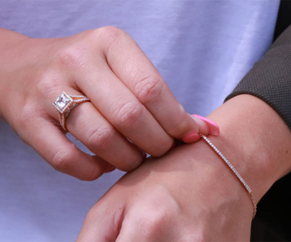 Woman wearing a princess-cut diamond engagement ring and a delicate white gold tennis bracelet