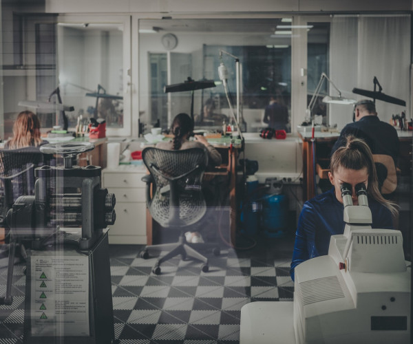 Jewelry workshop with artisans at microscopes and benches in a modern Antwerp showroom