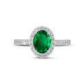 Halo solitaire ring in white gold with an oval emerald and small diamonds