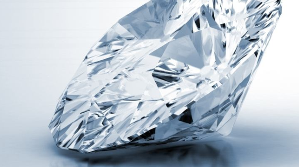a large treated diamond glimmers on a white surface, appearing brilliant even though it's of lower quality.