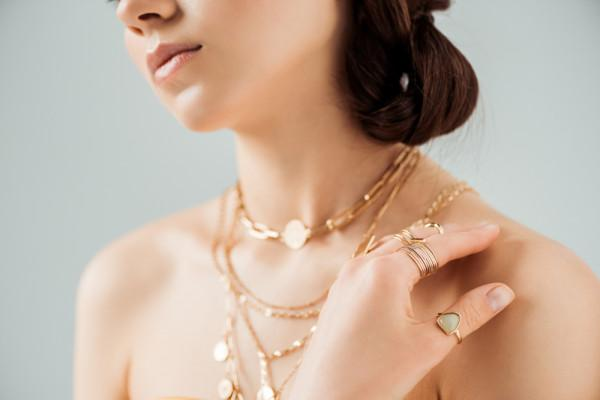 a woman layering multiple red gold necklaces, offering a sophisticated and classy look