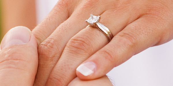 Platinum solitaire engagement ring with a square princess-cut diamond on a woman’s hand
