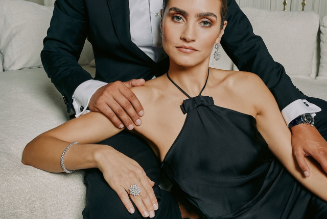 Woman wearing a black halter dress with diamond bracelet, floral diamond ring, and chandelier earrings