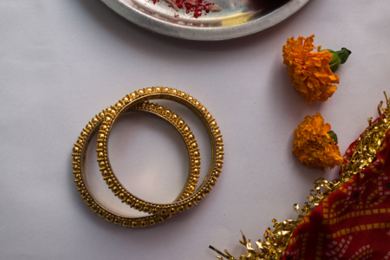 A collection of traditional gold bangles surrounded by vibrant flowers on a beautifully arranged table.