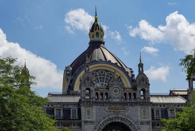 Historic Antwerp Central Station dome and facade beneath a blue sky with clouds