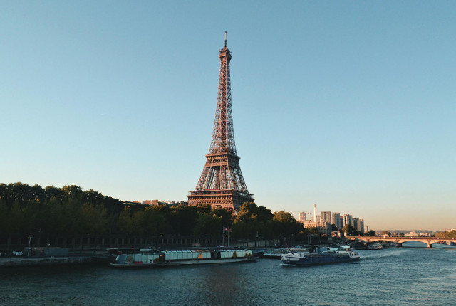 Eiffel Tower over the Seine in Paris with riverboats and a clear blue sky