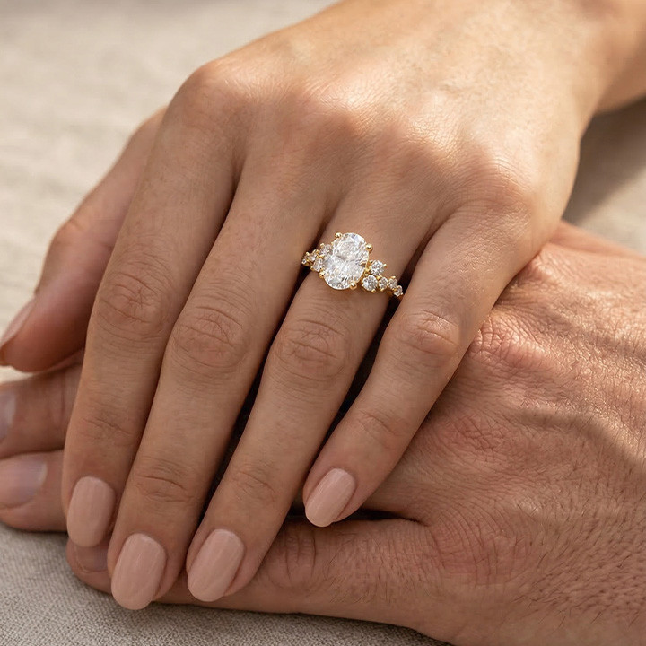 Yellow gold cluster engagement ring with oval center diamond and small side diamonds