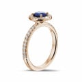 Halo solitaire ring in red gold with a round sapphire and small diamonds