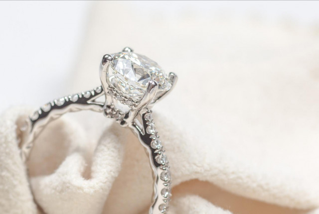 Anillo de compromiso de oro blanco con diamante central talla oval y pavé lateral en engaste catedral