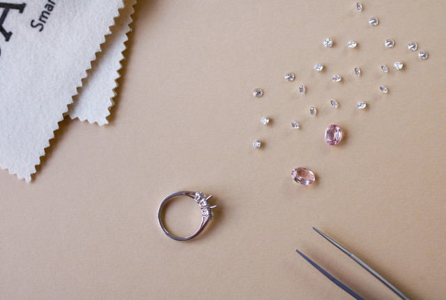 Anillo de compromiso en oro blanco con diamantes, visto en proceso de engaste Imagen de una mesa de trabajo donde se encuentran distintas piedras preciosas para ilustrar cuánto cuesta un anillo de compromiso