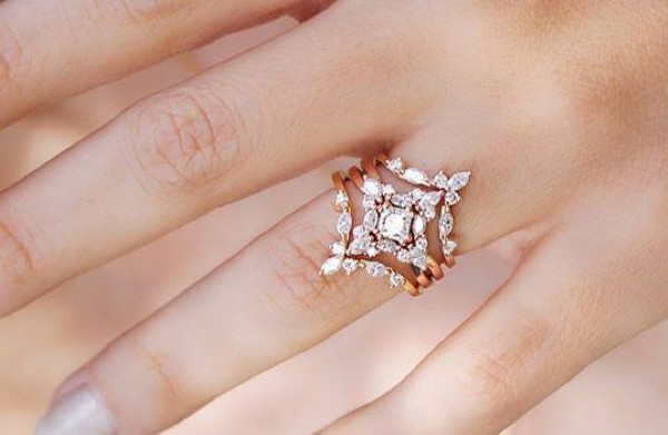 Anillo de oro rosa con diamantes, diseño floral calado y centro brillante en la mano