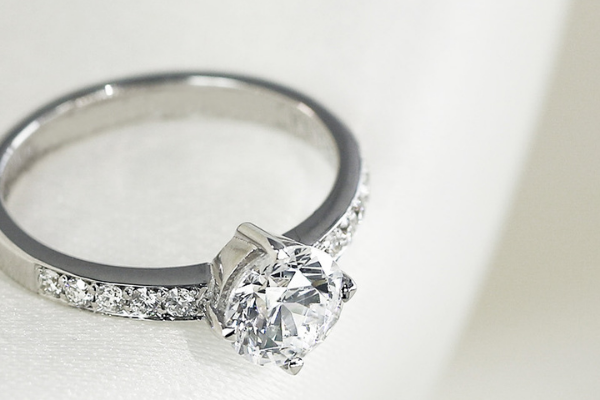 Anillo de compromiso de oro blanco con diamante central talla brillante y pavé lateral