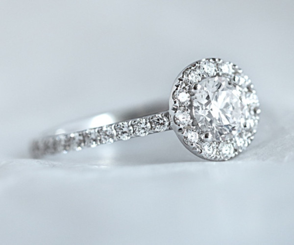 Anillo de compromiso de oro blanco con diamante central ovalado y halo de diamantes pavé