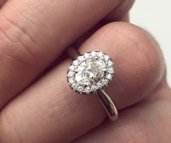 Anillo de compromiso en oro blanco con diamante central talla europea y halo de pequeños diamantes
