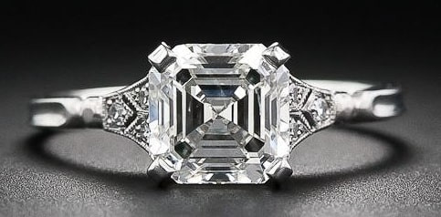 Anillo de compromiso de oro blanco con diamante central talla esmeralda y detalles art déco
