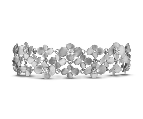 Pulsera ancha de oro blanco con flores mate y diamantes engastados en el centro