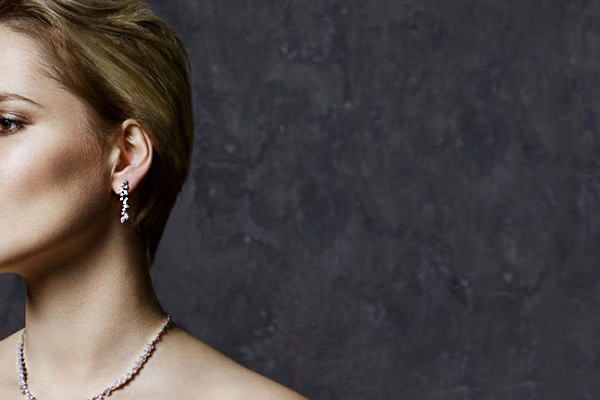 Mujer con pendientes colgantes de diamantes en oro blanco y collar a juego, estilo elegante