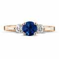 Anillo trilogía en oro rojo con zafiro central y diamantes redondos