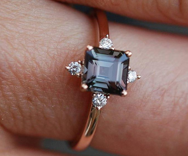 Anillo de oro rosa con diamante central cuadrado oscuro y pequeños diamantes laterales en engaste floral