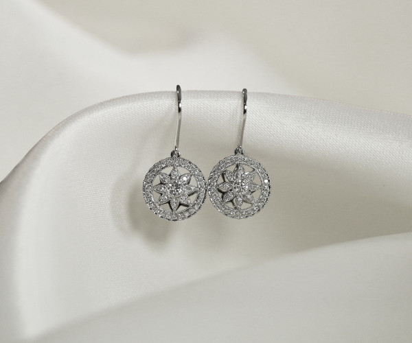 Boucles d’oreilles pendantes en or blanc serties de diamants, motif rosace ajourée en forme d’étoile.