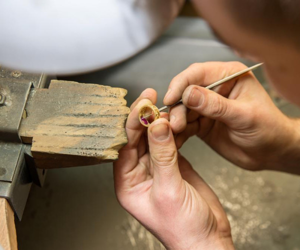 Un artisan grave des bagues de fiançailles sur du bois avec un outil avec la plus grande précision