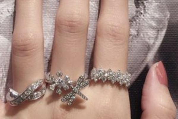 Main ornée de trois bagues en or blanc serties de diamants, au style floral et croisé.